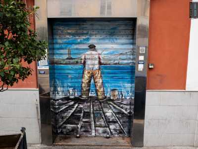 ...mentre in via Crispi un pescatore di spalle, col berretto nero in testa e i secchielli di latta ai piedi, sponsorizza il negozio specializzato Arbore
